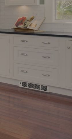 A kitchen with a Cadet heater built into the plinth under the cupboards